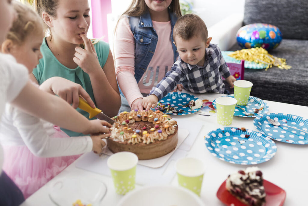 Niños sentados en la mesa junto a una tarta